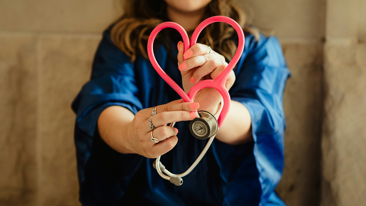 Nurse in blue jacket holding red and silver ring by Patty Brito